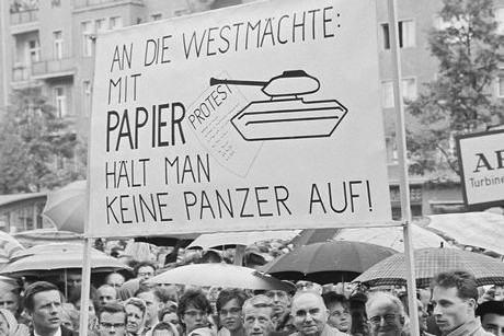Schwarz-Weiß-Aufnahme einer Demonstration. Deutlich ist das Plakat zu sehen: „An die Westmächte: Mit Papier hält man keine Panzer auf!“.