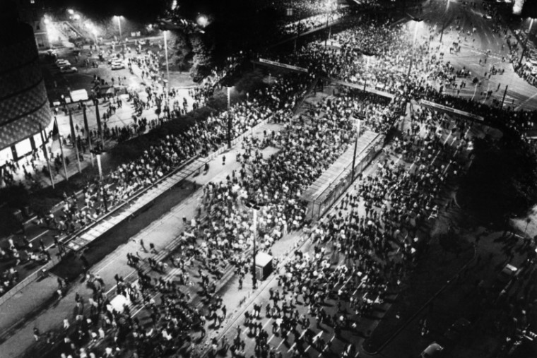 Luftaufnahme in Schwarz-Weiß von einer Montagsdemonstration in Leipzig. Zu sehen sind Menschenmaßen, die über eine Straße laufen.