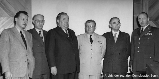 Willy Brandt steht neben Fritz Erler, Carlo Schmid, Günter Klein sowie dem Kommandeur der Air Base Lackland Wycliffe E. Steele. Fotografie in Schwarz-Weiß. Öffnet eine Auflistung der Reisen in den Jahren von 1945 bis 1956.