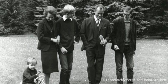 Willy Brandt geht mit Ehefrau Rut und seinen Söhnen Peter und Lars im Garten spazieren. Sohn Matthias sitzt auf einem Gokart. Fotografie in Schwarz-Weiß. Öffnet weitere Informationen zu seinen Kindern.