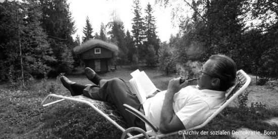 Willy Brandt sitzt, lesend und Pfeife rauchend, in einem Liegestuhl im Garten. Fotografie in Schwarz-Weiß. Öffnet weitere Informationen zu seinen Interessen und Hobbies.