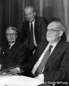 Willy Brandt steht hinter den sitzenden Herbert Wehner und Hans-Jochen Vogel. Fotografie in Schwarz-Weiß. Öffnet Abschnitt T bis Z der Liste der Weggefährten Brandts. Sortiert nach Nachnamen.